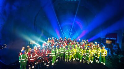 Feiringen av det siste gjennomslaget på Fornebubanen inne i en tunnel lyssatt med blått lys.