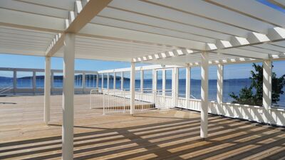 Terrasse med pergola over deler av terrassen, utsikt mot havet.