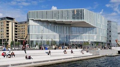 Deichman Bjørvika med mennesker langs brygga og Oslofjorden.