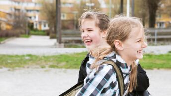 To barn ler i og leker i skolegården en vårdag.