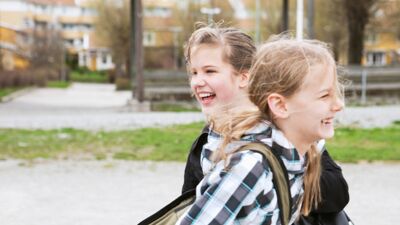 To barn ler i og leker i skolegården en vårdag.