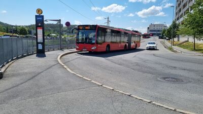 Bildet viser et busstopp ved Skullerud T-banestasjon. En rød buss, nummer 76 til Helsfyr, står ved busstoppet.