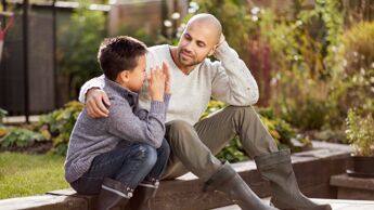 Bildet viser en far og sønn som sitter og snakker