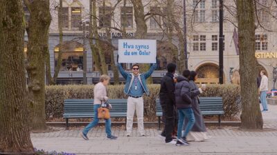 Bilde av mennesker på en gate i Oslo - en som holder plakat med teksten: "Hva synes du om Oslo?"