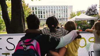 Tre barn holder rundt hverandre og ser på en bygning.