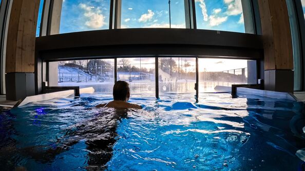 Mann svømmer i basseng.