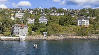 Utsikt til eiendommer langs sjøen i grønnkledd ås nedenfor Mosseveien