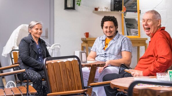 Tre personer smiler i en sofagruppe