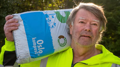 Mann i gul jakke med jordsekk på skulderen