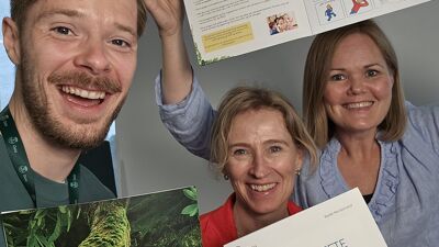 Tre personer som holder en brosjyre hver
