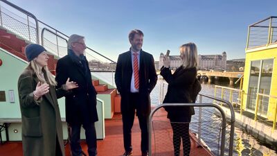 tre byråder og generalsekretæren i Oslo Badstuforening står utenfor en av badstuene og prater i sola