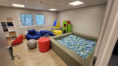 Lekerom med fargerike puter, treningsutstyr og stort ballbasseng.