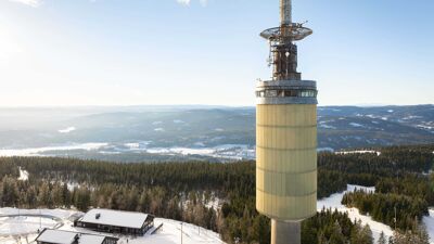 Dronefoto av tryvannstårnet med skog i bakgrunn.