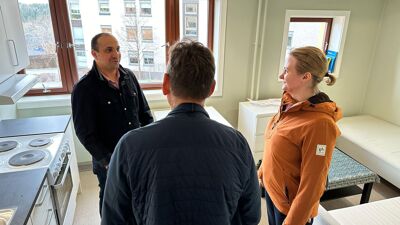 Bildet viser tre mennesker som står i et kjøkken på en av de nye flyktningboligene.