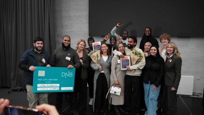 Flere mennesker står med byråd for sosiale tjenester og ordfører, med en stor sjekk.