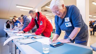 Langbord med folk som lager plakater til frivilligbørsen