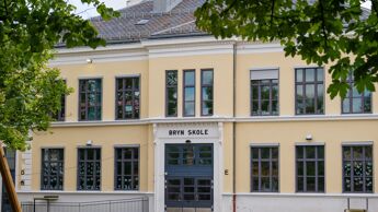 Fasaden til skolebygg i gul tegl. Vinduer med sprosser.