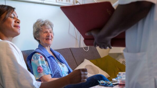 Pasient på Lindeberghjemmet i hyggelig samtale med helsearbeidere.