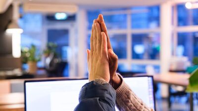 To hender gir high five foran datamaskin innendørs.