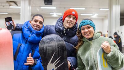 Tre personer som smiler, holder snowboard