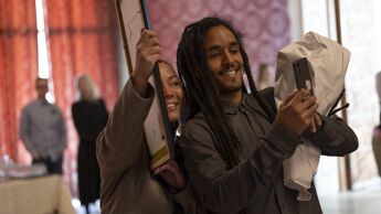 To personer smiler og tar selfie med diplomet.