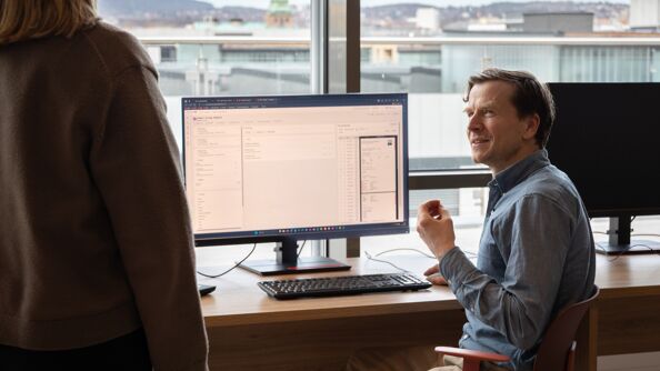 En mann som sitter foran en PC-skjerm på et kontor.