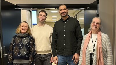 Fire personer ser på mot kamera og smiler.