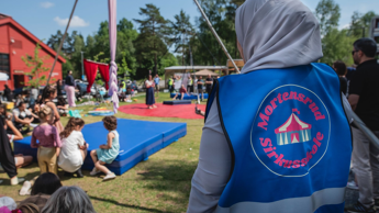 Bildet viser Mortensrud sirkusskole med barn i bakgrunn og en frivillig voksen med ryggen til.