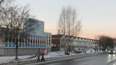 Bygninger langs en gate i grått vintervær. To mennesker går på fortauet.