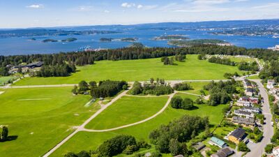 Oversiktsbilde av grønn slette. Oslofjorden i bakgrunnen.