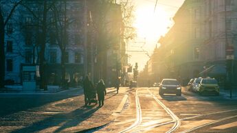 Krysset Kirkegata og Stortorvet sett mot Karl Johans gate mellom Domkirken og Stortorget en januar ettermiddag. Solnedgang, mennesker på tur med barnevogn og taxiholdeplass med biler som venter.