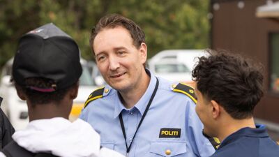 To skoleelever i hyggelig samtale med politimann.