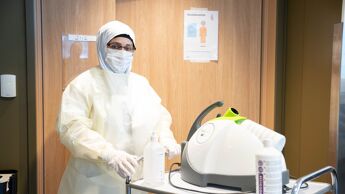 Ansatt i hvitt smittevernutstyr.