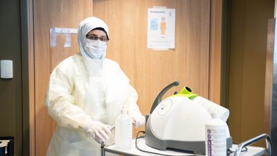 Ansatt i hvitt smittevernutstyr.