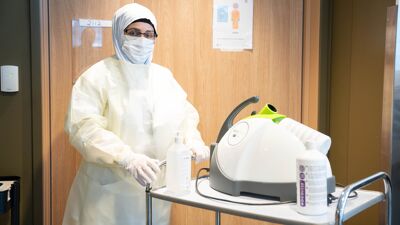 Ansatt i hvitt smittevernutstyr.