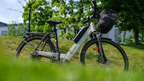 Elektrisk hvit og grønn sykkel merket med NAV Bydel Ullern. Sykkelen står i en grønn eng.