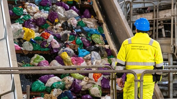 Poser i ulike farger på bånd i itsorteringen på Haraldrud gjenvinningsstasjon. En mann i gul dress og blå hjelm passer på.