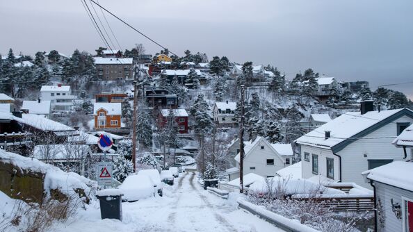 Vinterbilde tatt fra Baglerfaret mot Simensbråten. Snø- og isdekt gate med eneboliger på hver side.