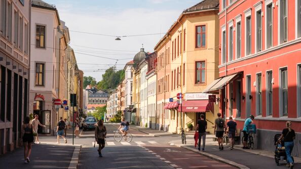 Rolig bygate med lave boligblokker og folk på sommerstid.