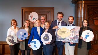 Bilde av byrådet i Oslo som holder fram forsiden på kommuneplanens samfunnsdel og ulike symboler for samfunnsflokene.