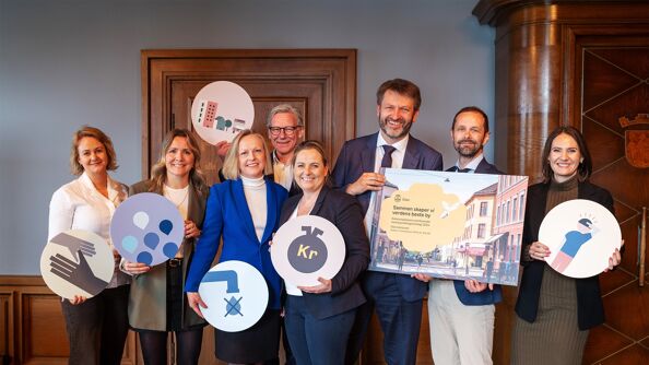 Bilde av byrådet i Oslo som holder fram forsiden på kommuneplanens samfunnsdel og ulike symboler for samfunnsflokene.