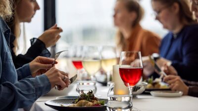 Selskap ved restaurantbord med mat og vin