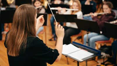 Bilde av en orkesterdirigent som står foran en gruppe musikere.