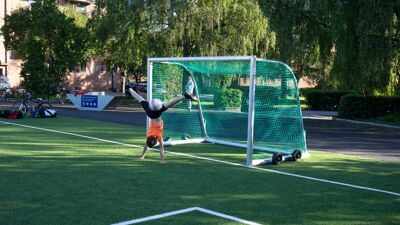 Person står på hendene foran et fotballmål.