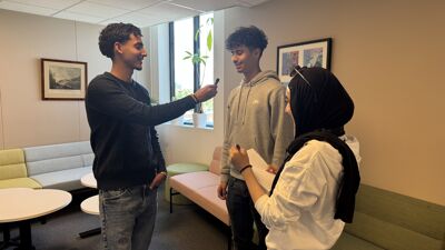 Tre ungdommer står oppreist. En blir intervjuet av de to andre.