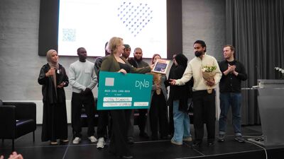 Julianne Ferskaug, byråd for sosiale tjenester, deler ut en sjekk til Ung Bjørdal på scenen under Oslo kommunes Frivillighetskonferanse 2025.