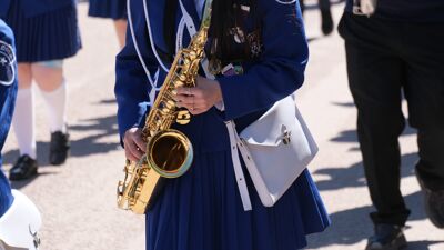 Nærbilde av korpsjente i 17. mai-tog som holder en saksofon.