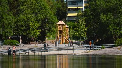 Svarttjern lekeplass med badevannet i forgrunnen.