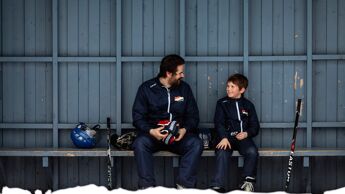 Bilde av voksen mann og gutt på rundt 10 år på en hockey-benk