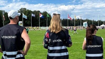 Tre personer med vest med Utekontakten på står og følger med på Norway Cup.